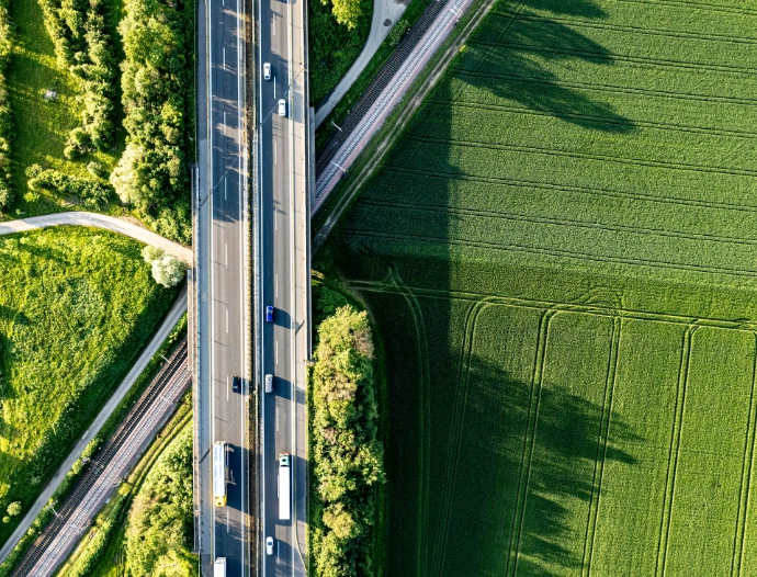 an aerial view of a highway in the middle of a green field