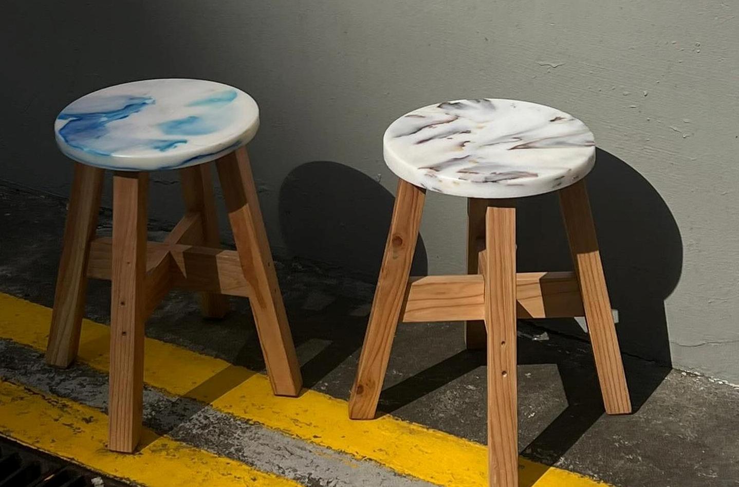 Modern eco-friendly stool featuring a vibrant, marbled recycled plastic top and minimalist metal frame.